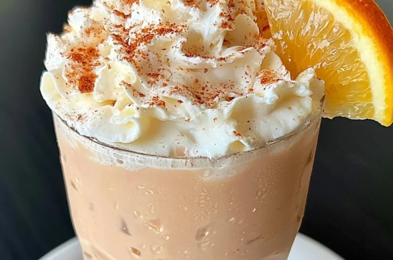 Cozy orange cinnamon milk tea served in a mug with spices and orange slices.