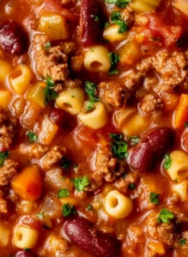 A comforting bowl of pasta and beans served with fresh herbs and cheese.