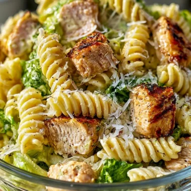 Creamy chicken caesar pasta salad garnished with fresh herbs and parmesan cheese.