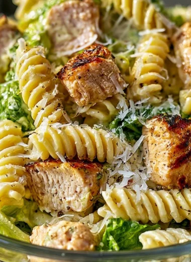 Creamy chicken caesar pasta salad garnished with fresh herbs and parmesan cheese.