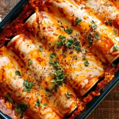 A plate of easy bean and cheese enchiladas topped with melted cheese and garnished.