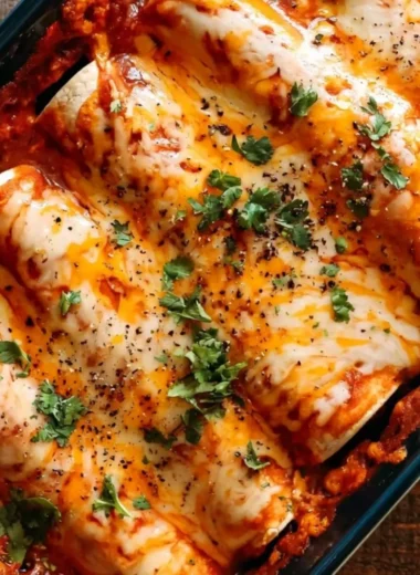 A plate of easy bean and cheese enchiladas topped with melted cheese and garnished.